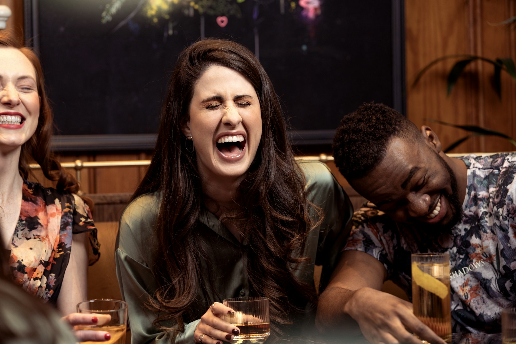 Friends laughing together over drinks at a bar